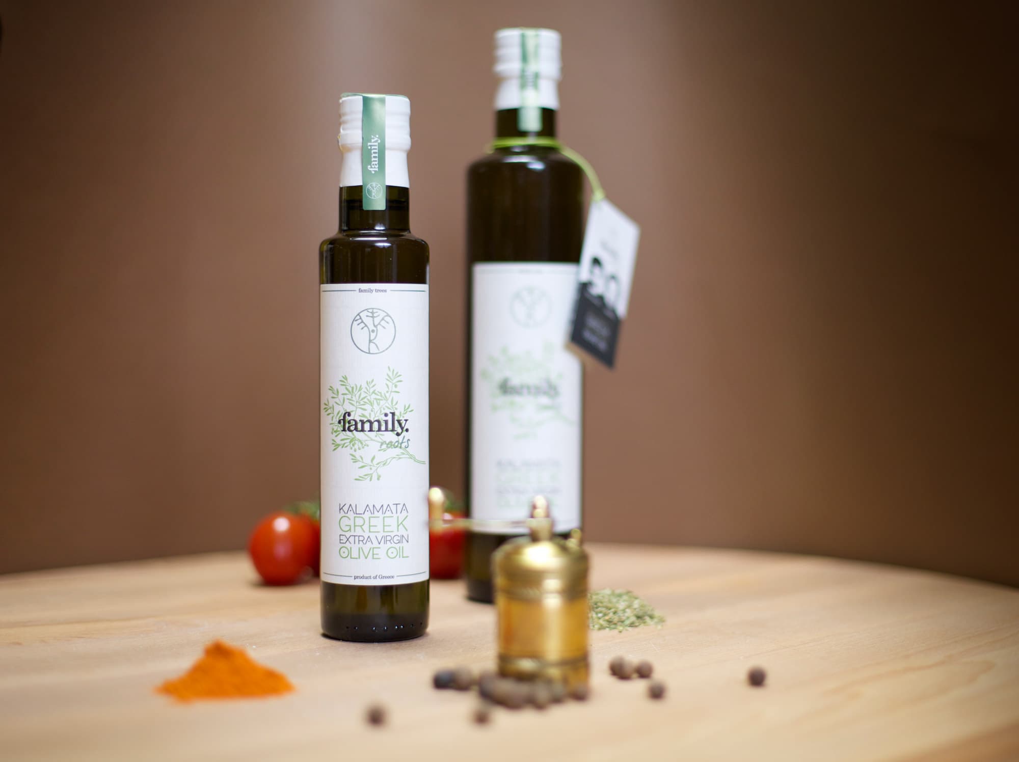 Botellas de aceite de oliva family. roots, de 250 ml y 500 ml, sobre una mesa de madera con un molinillo de pimienta