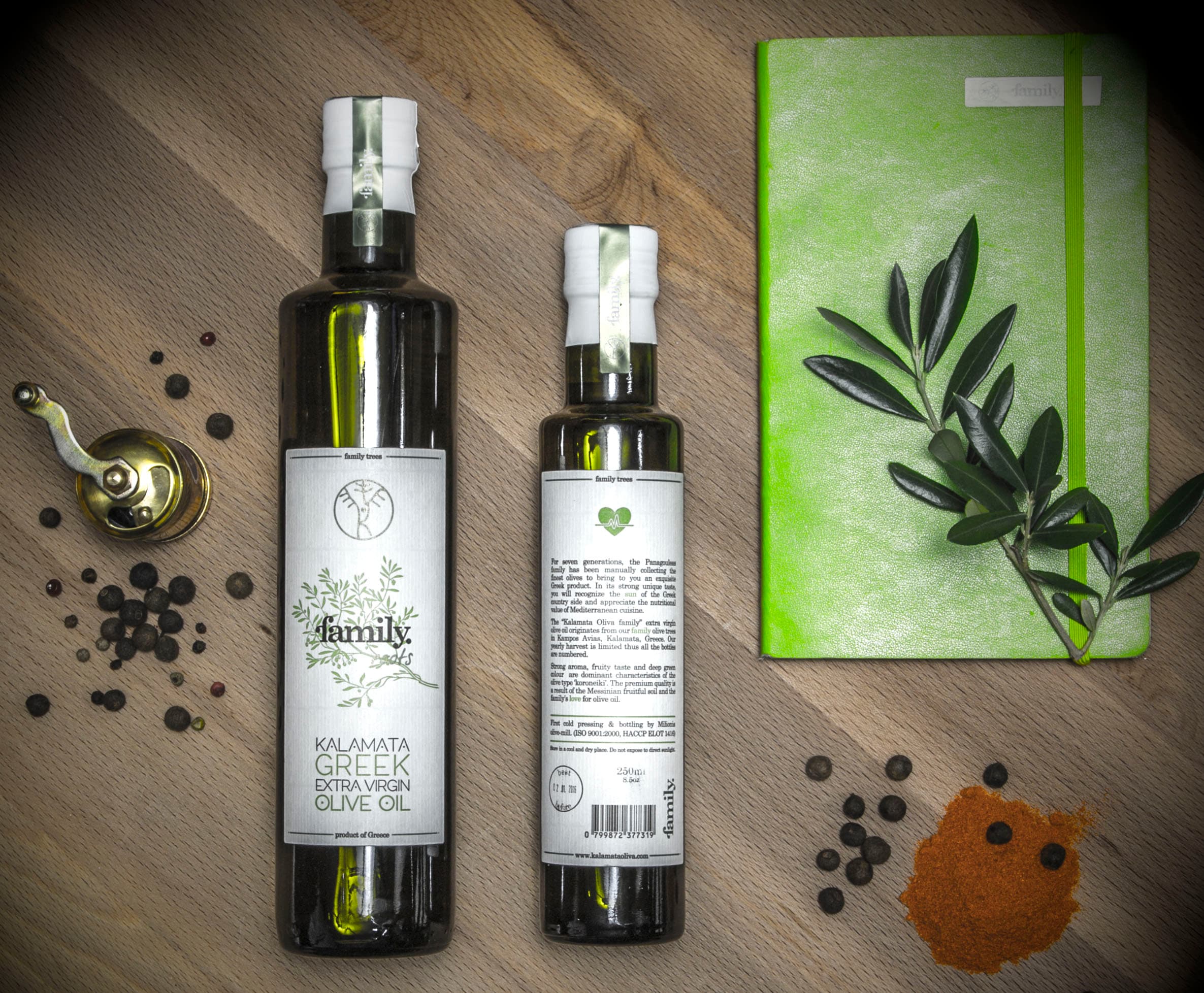 Botellas de aceite de oliva family. roots, de 500 ml y 250 ml, vistas desde arriba junto a una ramita de olivo