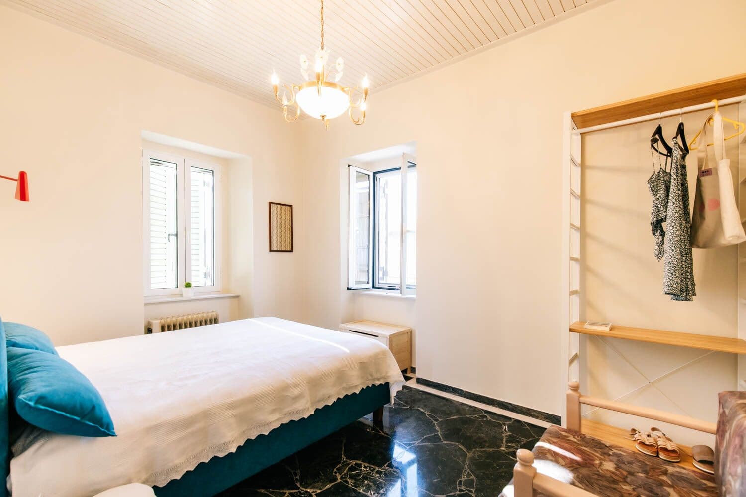 Dormitorio con cama de matrimonio, lámpara de araña y un perchero abierto